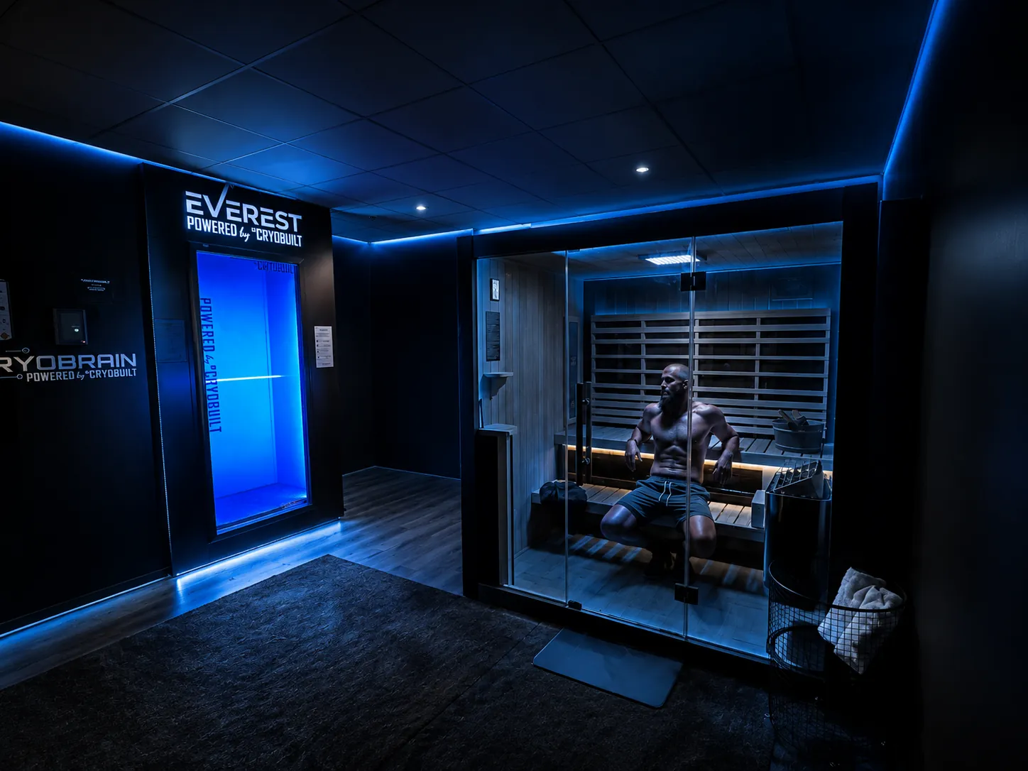 Contrast therapy room at Defiant Health in Lisle, IL — cryotherapy chamber on the left and infrared sauna on the right, lit in blue